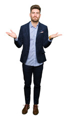 Young handsome bussines man clueless and confused expression with arms and hands raised. Doubt concept.