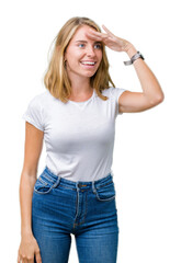 Fototapeta premium Beautiful young woman wearing casual white t-shirt over isolated background very happy and smiling looking far away with hand over head. Searching concept.