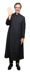 Middle age priest man wearing catholic robe showing and pointing up with fingers number five while...