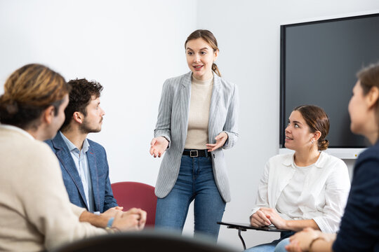 Young female professor explaining subject to classroom full of students