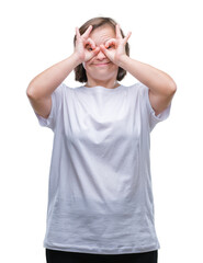 Fototapeta premium Young adult woman with down syndrome over isolated background doing ok gesture like binoculars sticking tongue out, eyes looking through fingers. Crazy expression.