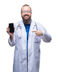 Young doctor man showing smartphone screen over isolated background with surprise face pointing finger to himself