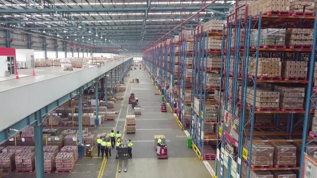 Delivery Warehouse full of shelves with goods in cardboard boxes, workers sort packages, move inventory with pallet trucks and Forklifts. Product Distribution Logistics Center. Asia. - Powered by Adobe