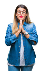 Young beautiful woman over wearing glasses over isolated background praying with hands together asking for forgiveness smiling confident.