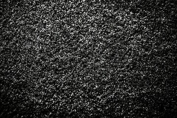 Textured black surface resembling fine gravel captured in soft lighting indoors at midday