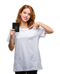 Fototapeta premium Young beautiful woman holding passport of canada over isolated background with surprise face pointing finger to himself