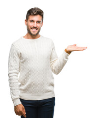 Young handsome man wearing winter sweater over isolated background smiling cheerful presenting and pointing with palm of hand looking at the camera.