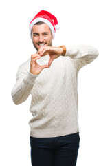 Young handsome man wearing santa claus hat over isolated background smiling in love showing heart symbol and shape with hands. Romantic concept.