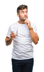 Young handsome man drinking glass of water over isolated background serious face thinking about question, very confused idea