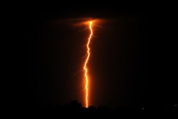 A lightning bolt is seen in the sky, illuminating the darkness