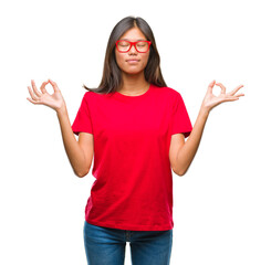 Young asian woman wearing glasses over isolated background relax and smiling with eyes closed doing meditation gesture with fingers. Yoga concept.