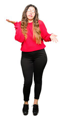 Young beautiful woman wearing red glasses clueless and confused expression with arms and hands raised. Doubt concept.