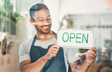 Window, waiter and coffee shop with open sign or poster in small business, cafe or bistro. Male person, hospitality and happiness as barista, entrepreneur or employee for welcome as restaurant staff