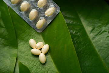 white softgels herbal medicine on leaves, capsules with vitamin E, Cod liver oil, DHA, Fish oil...