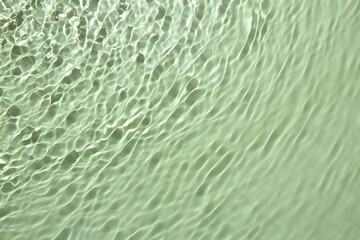 Fototapeta na wymiar Rippled surface of clear water on light green background, top view