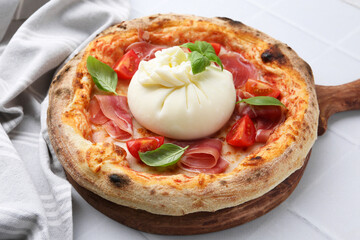 Delicious pizza with burrata cheese, basil, tomato and ham on white table, closeup