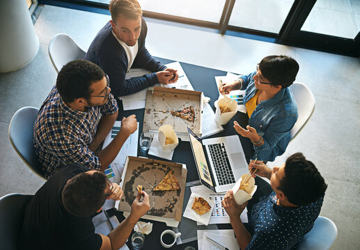 Creative, discussion and business people in meeting with pizza, planning and collaboration from above. Eating, laptop and team in workshop for development stats, growth or data analysis in office