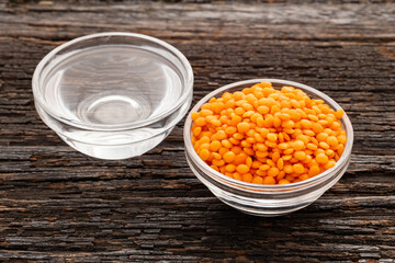 Red lentils in a bowl and clean water in a bowl - Lens culinaris.