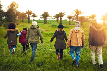 Back, field and walking with group, adventure and bonding together with happiness. Outdoor, people and friends with nature, grass and environment with weekend break, vacation and holiday with joy