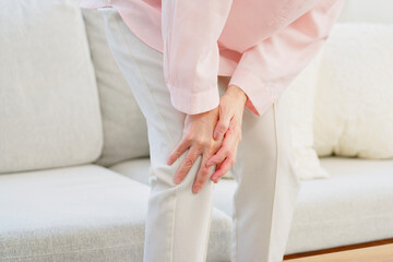 膝が痛いシニア女性　リビングルーム　顔無し