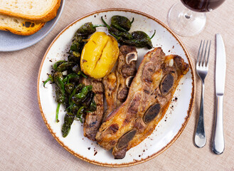 Steak churrasco with slices of fried potato and little green peppers served in a plate