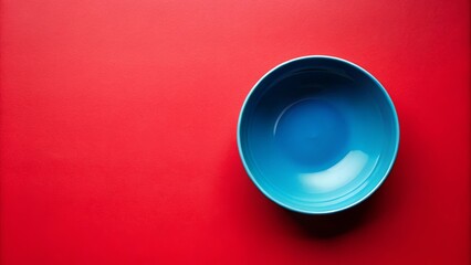 A single blue ceramic bowl on a solid red background, a minimalist composition highlighting the contrast of colors and textures.