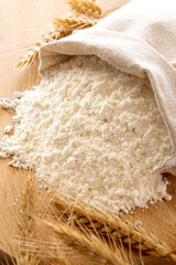close up a bag of wheat flour on wooden background.