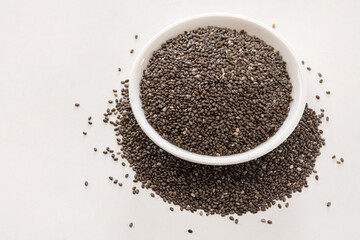 a dish of raw chia seeds on white background.