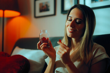 Happy Woman Taking Vitamin Gummy Bears. Cheerful lady enjoying health boosting natural supplements 
