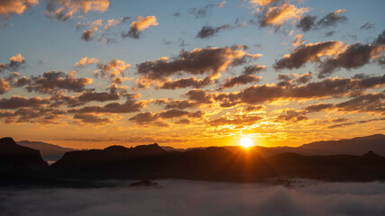 Fototapeta premium Sunset mountain range beautiful landscape mist foggy sunrise beam. Golden sky Mountain landscape foggy windy mountain. Amazing Landscape cloud sky on sunrise. Countryside gold sunlight heaven scene
