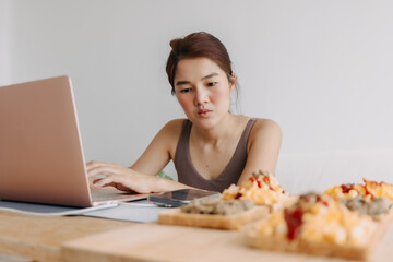 Asian woman is working at home with cozy clothes and breakfast meal.