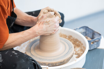 Close-up of a potter's hands working on a pottery wheel. 