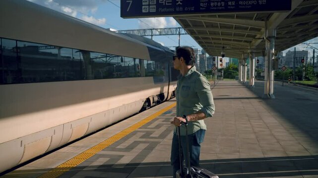 Man Traveler in 40s with Trolley Suitcase Standing on Railway Platform Waiting His Train At Seoul Train Station in Summer