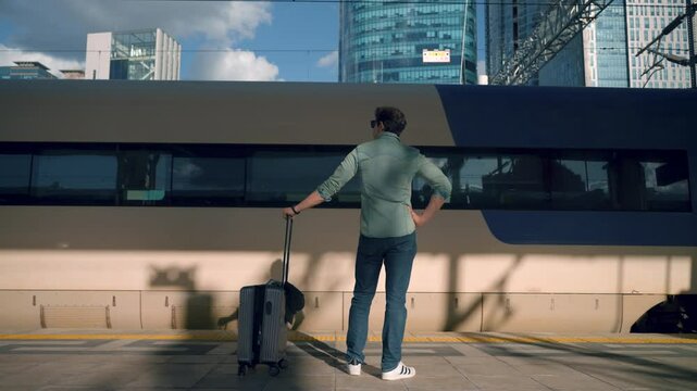 Rear View of Man Traveler with Travel Suitcase Standing At Railway Platform At Seoul Station Facing Departing KTX Train