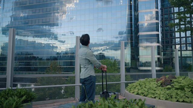 Tourist Man in $0s With Suitcase Looking Up Admiring Tall Skyscrapers in Seoul Downtown Seoullo 7017 Skygarden at Sunset - gimbal push in