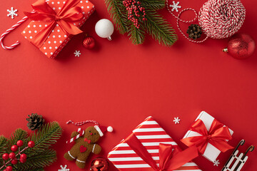 Top view of beautifully wrapped Christmas gifts with red ribbons, surrounded by festive decorations and greenery on a vibrant red background