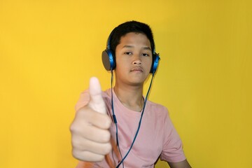 A teenager is enjoying music with their headphones on while giving a thumbs-up.