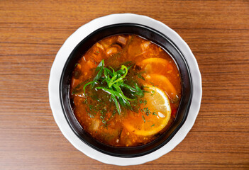 Russian soup Solyanka on wooden table side view