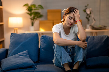 A woman is sitting on a couch with her head in her hands