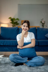A woman is sitting on the floor with a blue pillow on her lap