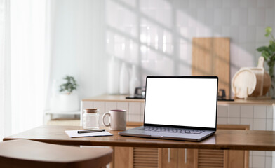 Open laptop with blank screen on a wooden desk in a kitchen room home office