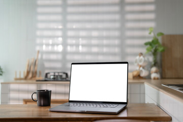 Open laptop with blank screen on a wooden desk in a kitchen room home office