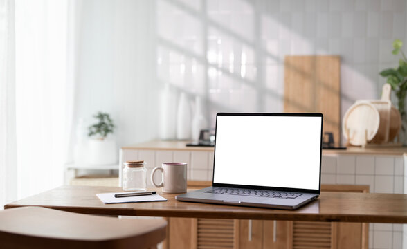 Open laptop with blank screen on a wooden desk in a kitchen room home office