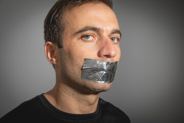 Caucasian man with tape on mouth.