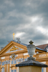 Historisierende Vase auf der Mauer des Stiftsparks von Melk vor dem Portalbau des Klosters und einem dramatischer Wolkenhimmel