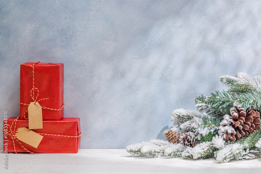 Aufkleber Christmas template featuring gift boxes and snowy fir tree branches on a table with shadows and sun glares softly falling on the wall