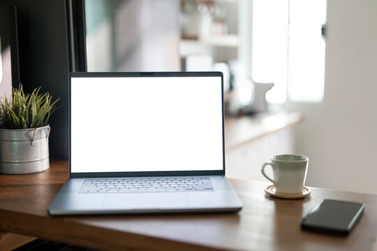 Open laptop with blank screen on a wooden desk in a kitchen room home office