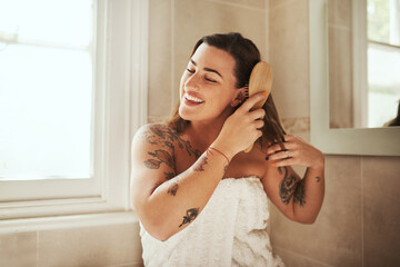 Woman, happy and brush hair in bathroom for morning routine, getting ready and haircare in home....