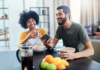 Happy, interracial couple and laughing with phone for breakfast, funny morning or social media at home. Young, man and woman with smile on mobile smartphone for comedy, humor or online app at house