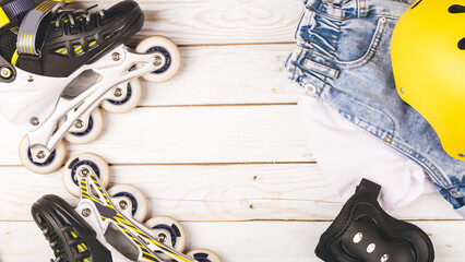 Top view of roller skates protective gear set - helmet and knee pads in black colors. wooden background flat lay